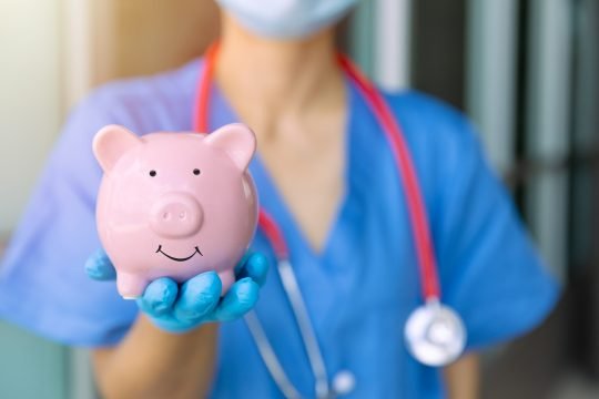 medical staff hand showing piggy bank smile for saving money for future healthcare health insurance concept